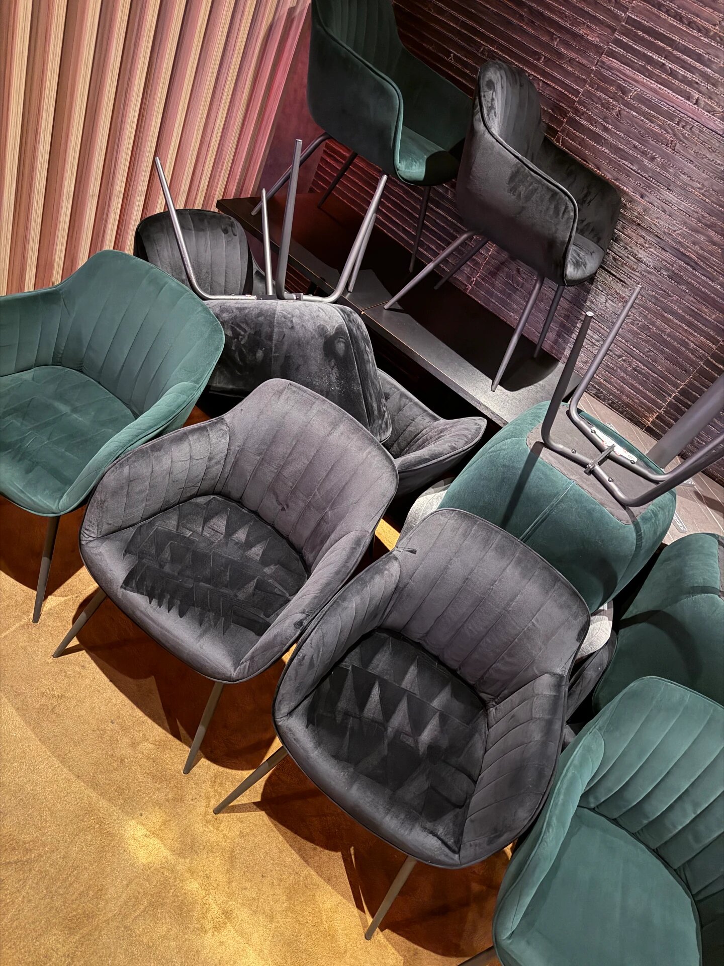 Groene en grijze fluwelen stoelen opstapeld voor reiniging in een horecazaak