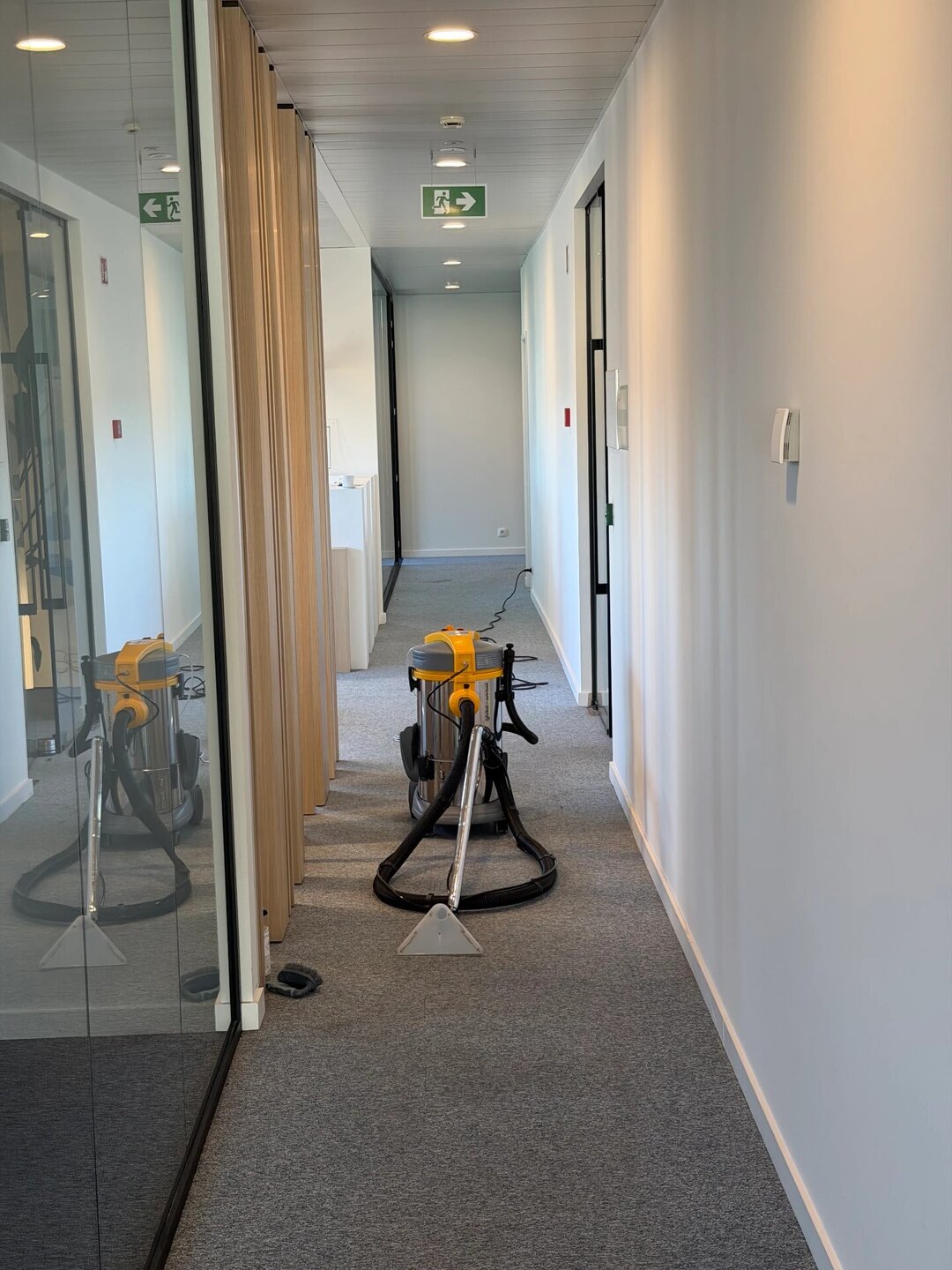 Extractiemachine in een kantoorgang met gereinigd grijs tapijt